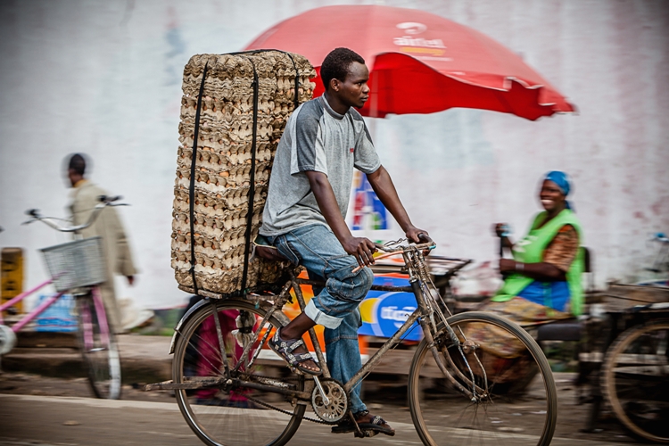 A man rides a bicycle on a market road in Dar es Salaam, Tanzania. Image by Oxford Media Library