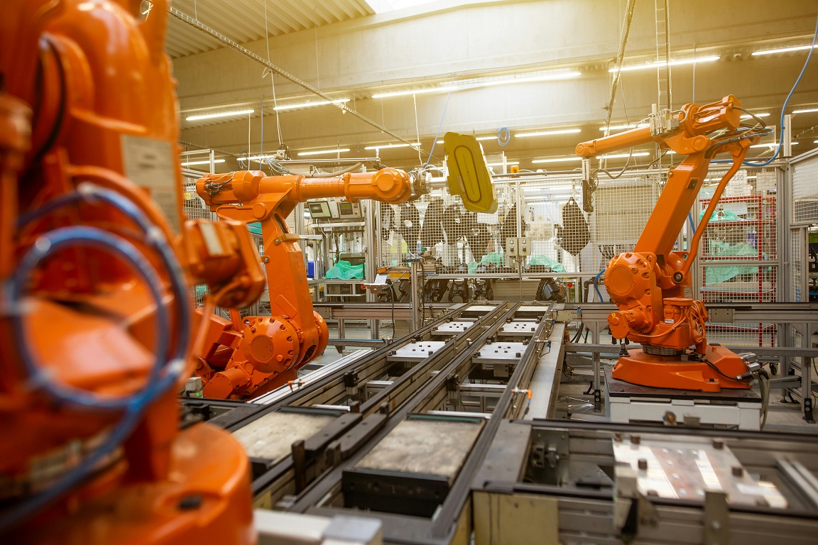 Orange industrial robots on an automated automotive assembly line